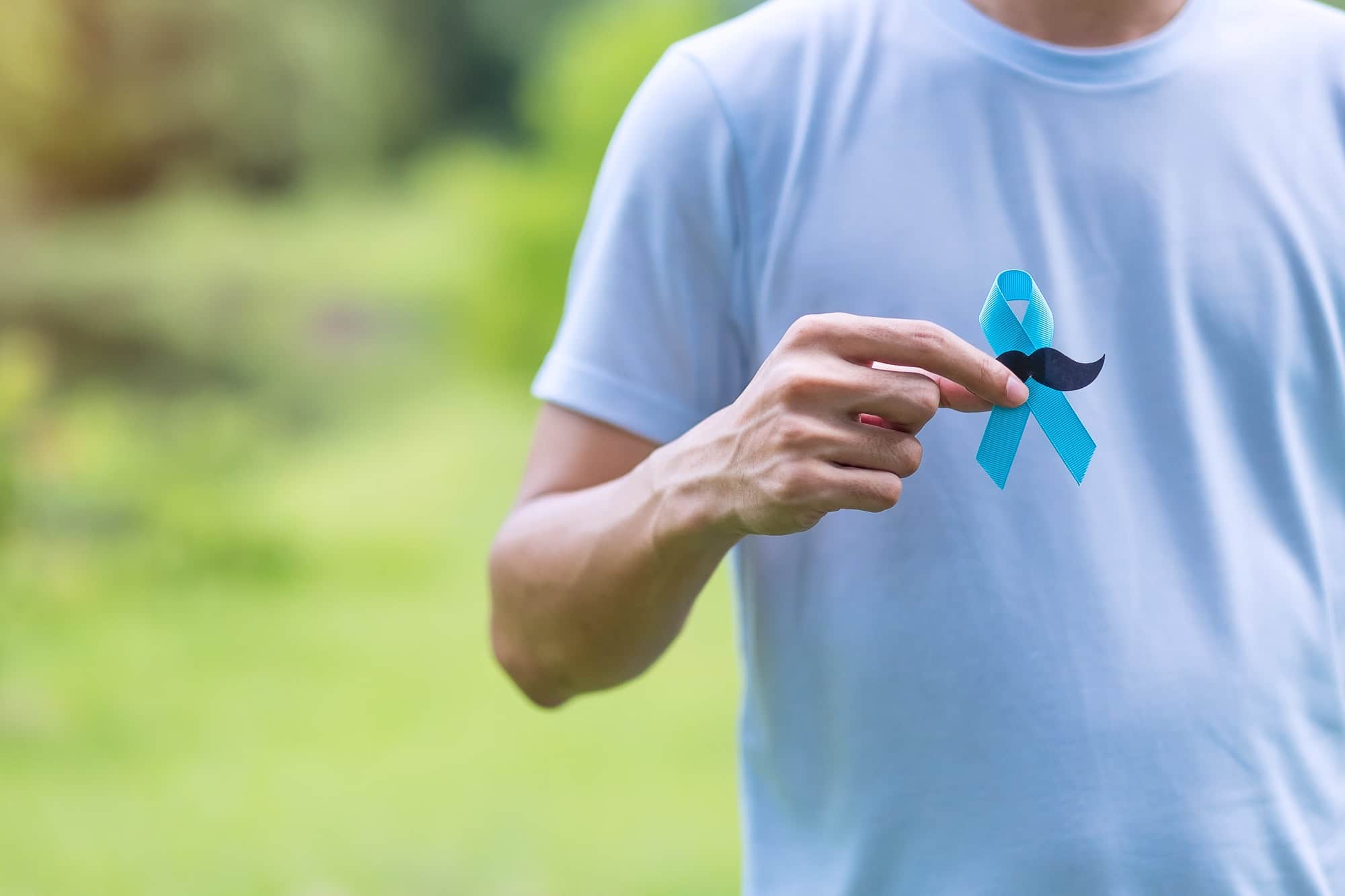 November Prostate Cancer Awareness month, Man in blue shirt with hand holding Blue Ribbon